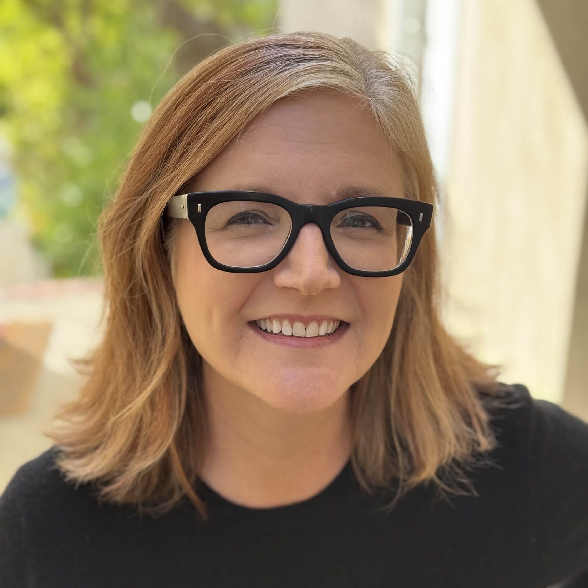 Photo: Portrait shot of Jennifer Getzinger, a young woman with shoulder length blonde hair and black glasses.