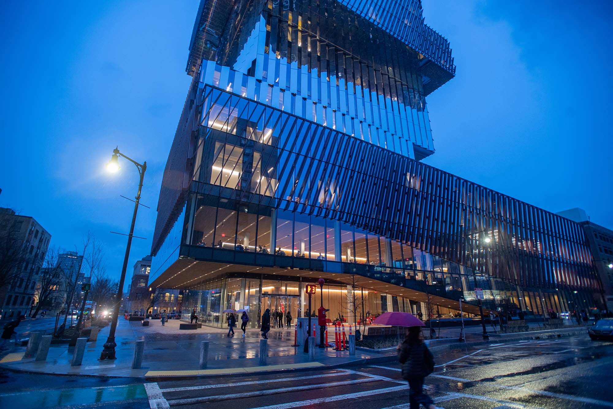 Photo: The CDS building on BU's campus, a tall glass structure, at night during the rain