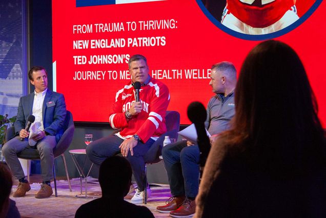 Photo: A former NFL player holding a mic on stage speaks to a crowd.