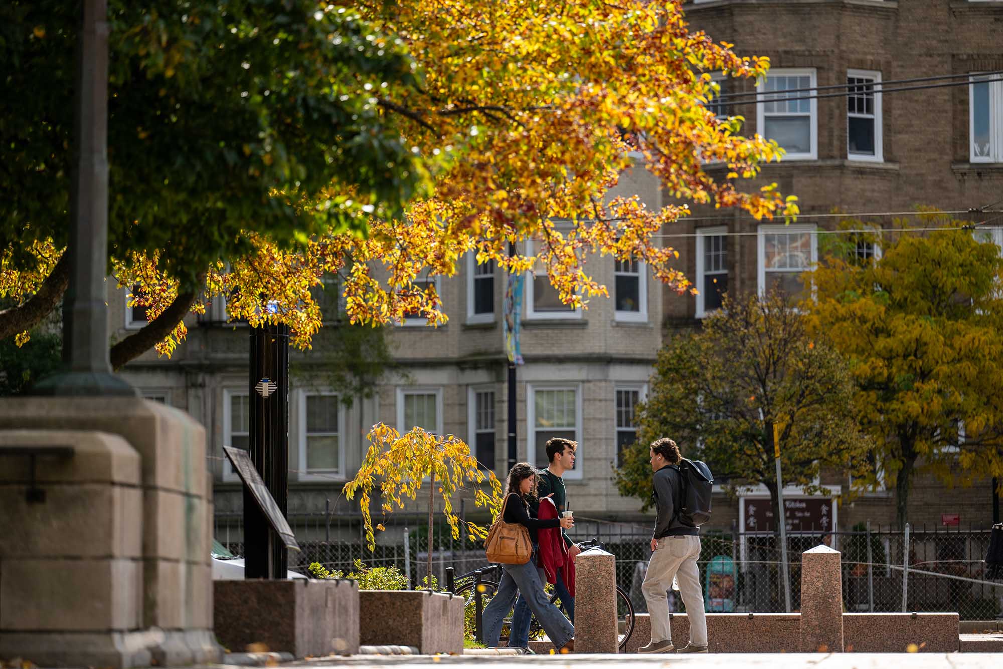 Photo: Campus shot in the fall of leaves changing with students milling about.