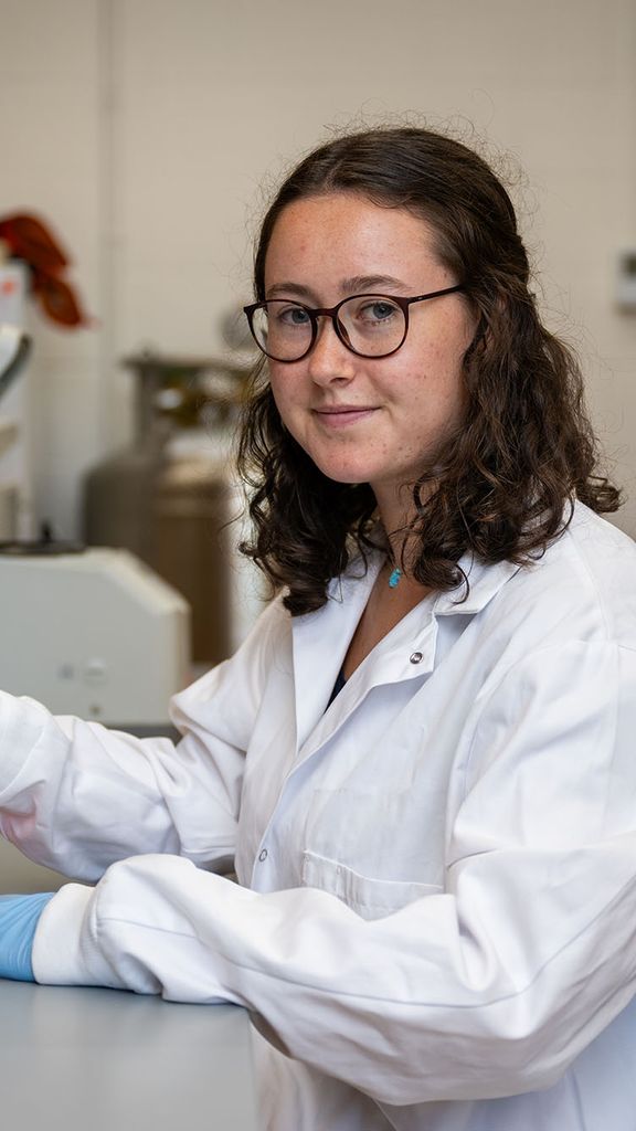 Photo: A researcher in a white lab coat pipes samples into dishes