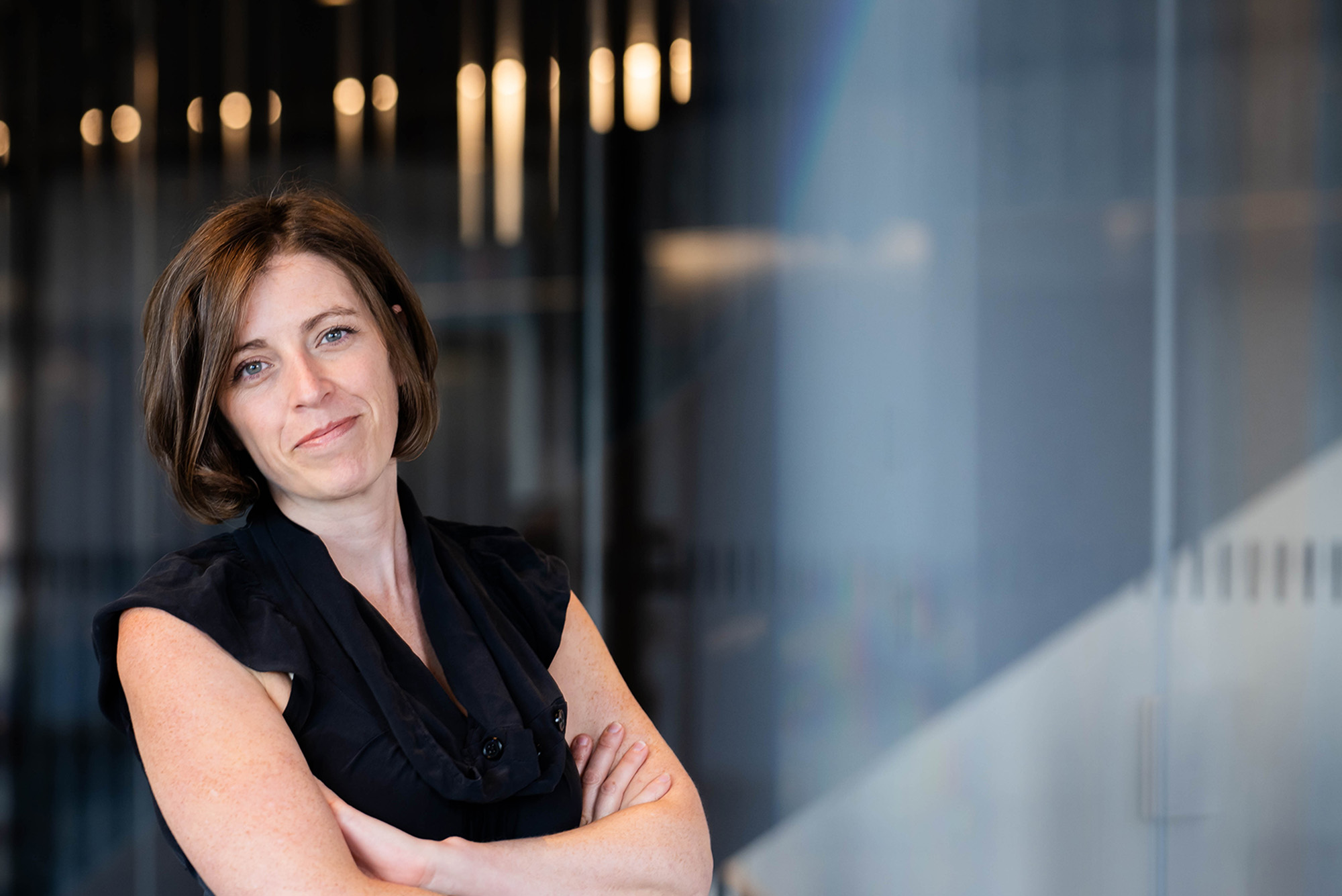 Photo: A woman with short hair leans against a blue wall in this posed formal portrait