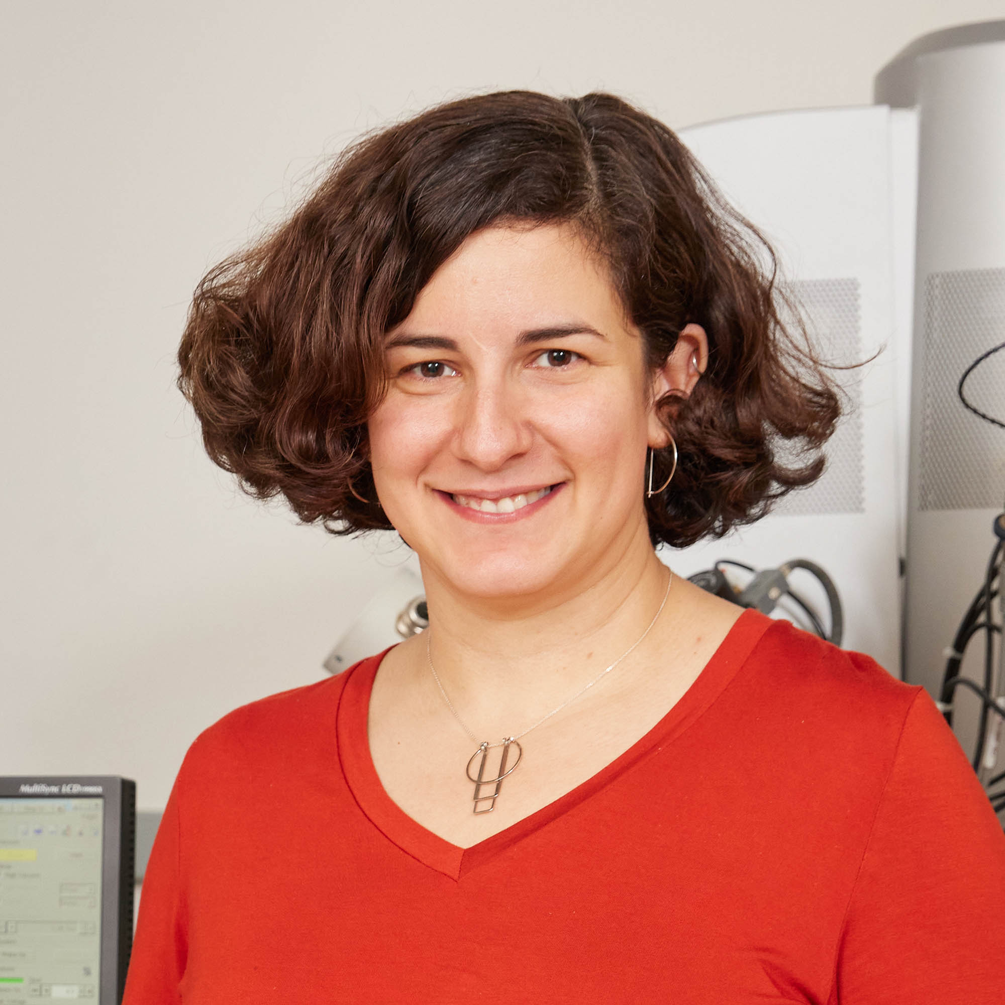 Photo: A square crop of an individual with short brown hair wearing a red sweater.