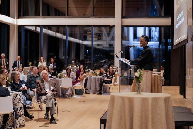 Photo: A wide shot of President Gilliam speaking to an audience of faculty in a large event space.