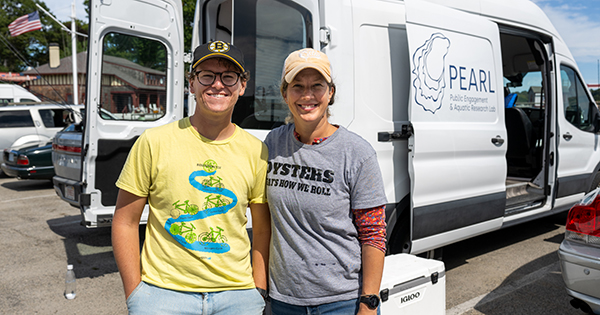 Photo: Two people smiling in front of the PEARL mobile oyster lab van
