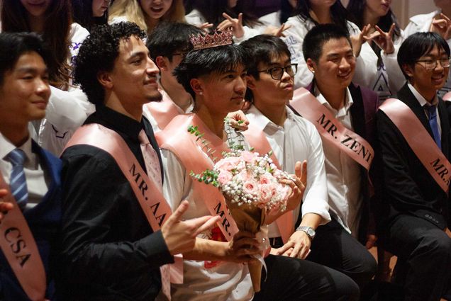 Photo: Various contestants with pink sashes and formal wear pose for a photo.