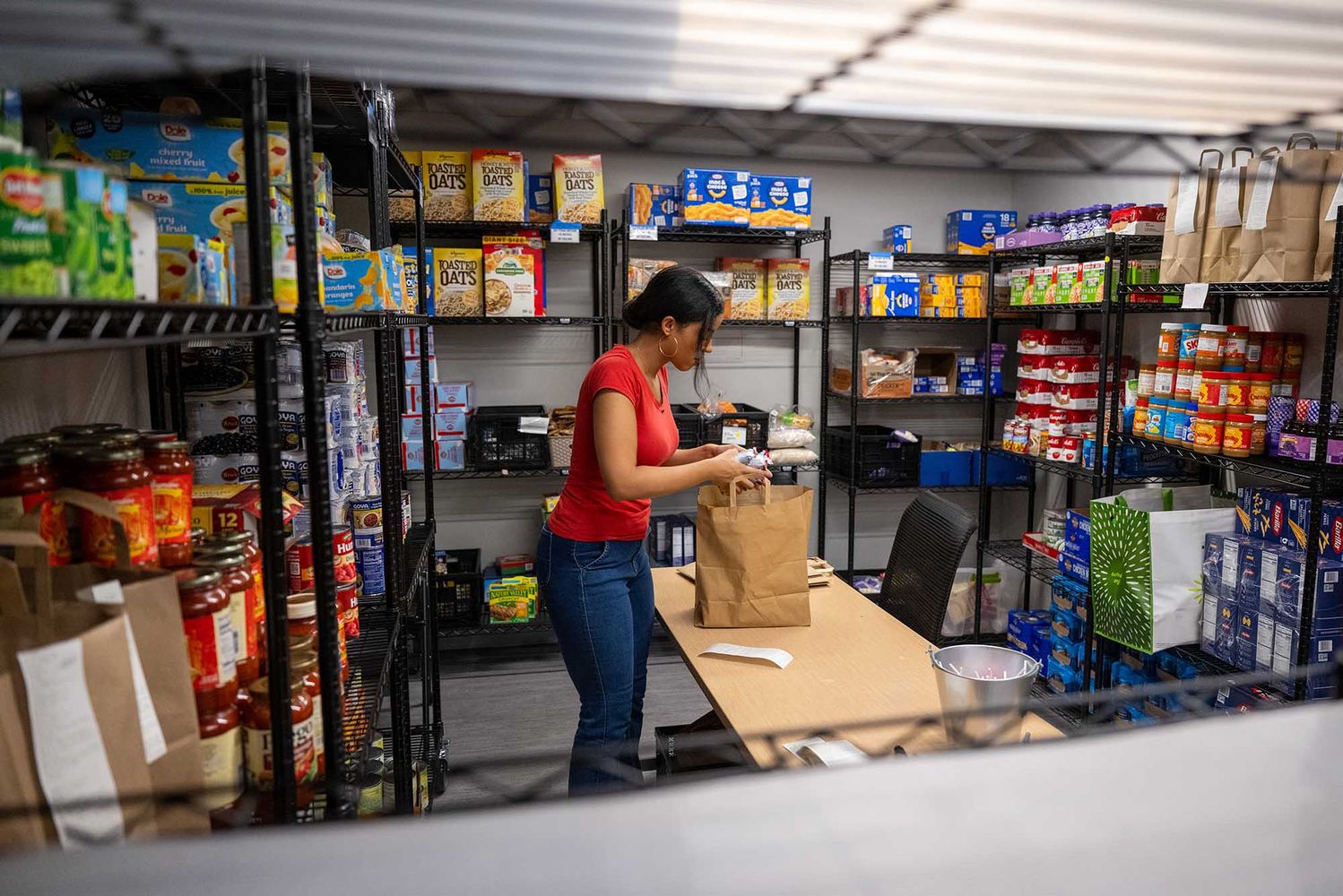Photo: A lone individual in a red shirt stocks and organizes the BU food pantry.