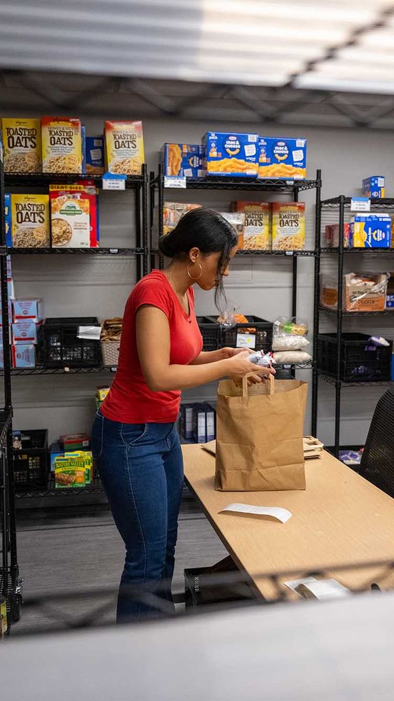 Photo: A lone individual in a red shirt stocks and organizes the BU food pantry.