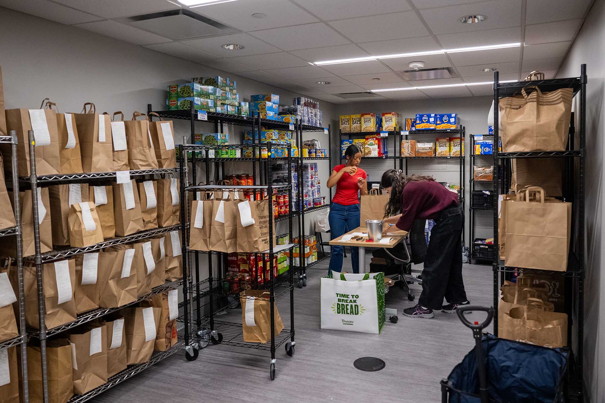 Photo: Two individuals work in the food pantry at BU, stocking and organizing.