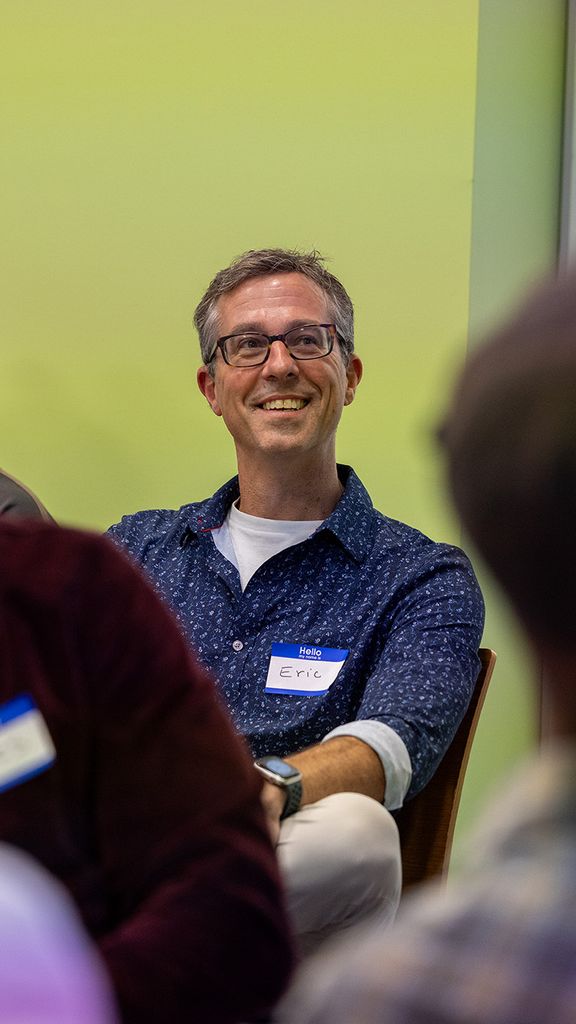 Photo: A group shot of people sititng in chairs with Eric Gordon, director of COM’s Center for Media Innovation & Social Impact, in the center