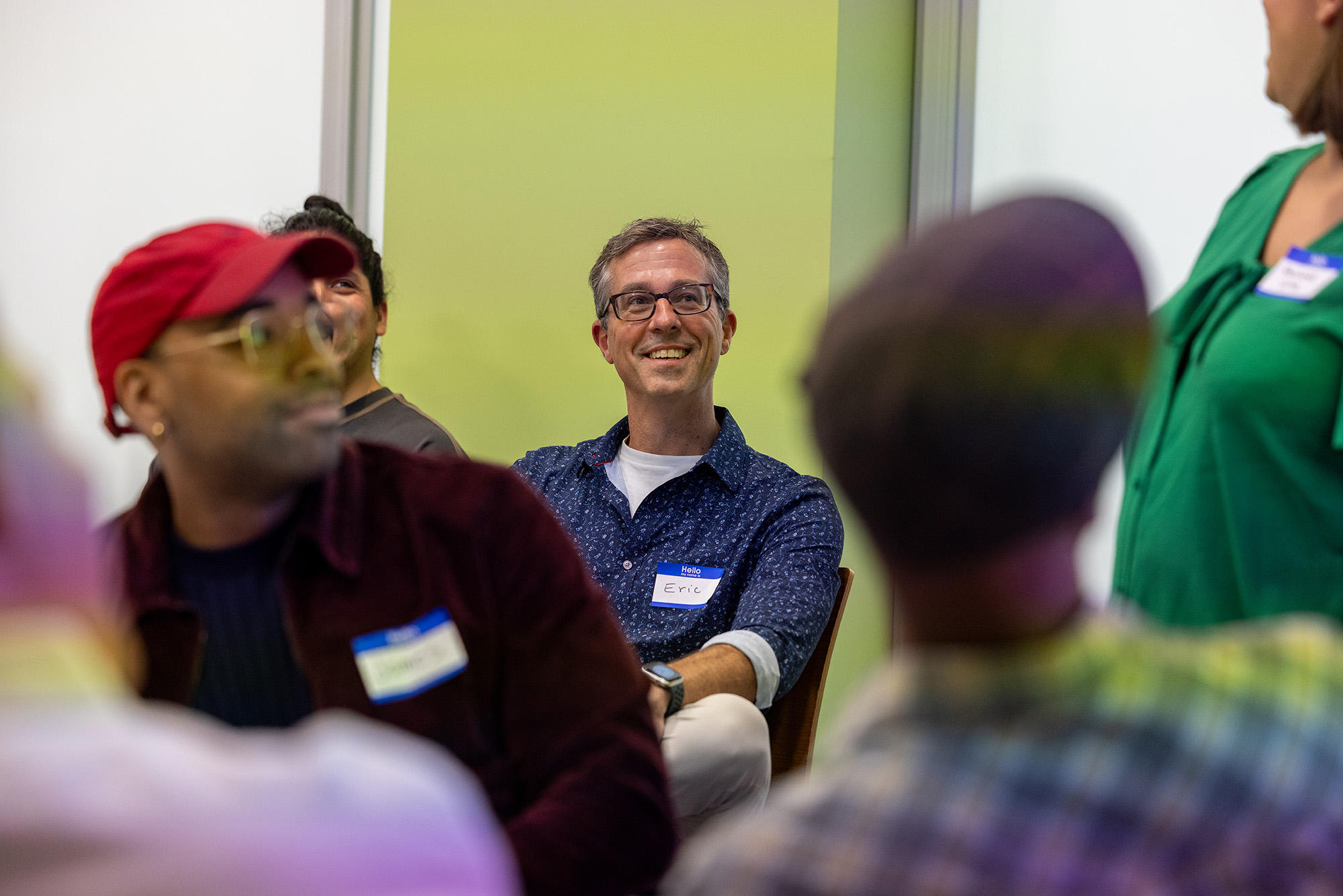 Photo: A group shot of people sititng in chairs with Eric Gordon, director of COM’s Center for Media Innovation & Social Impact, in the center
