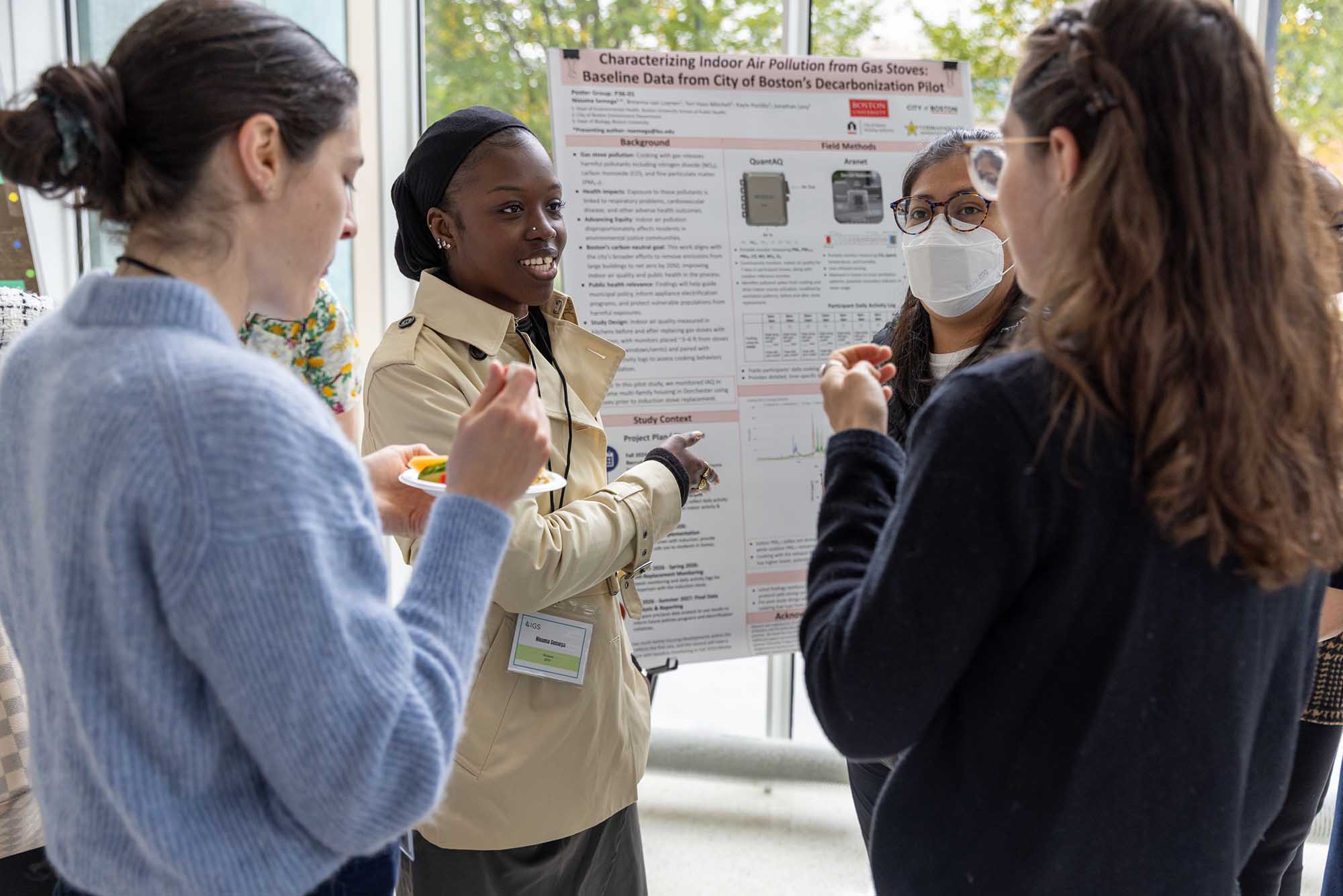 Photo: A group of individuals chat around an information board showing their work.
