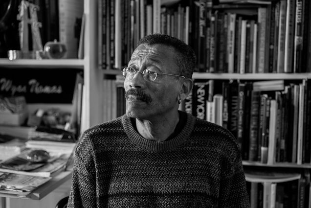 Photo: A black and white photo of production designer Wynn Thomas in front of a bookshelf