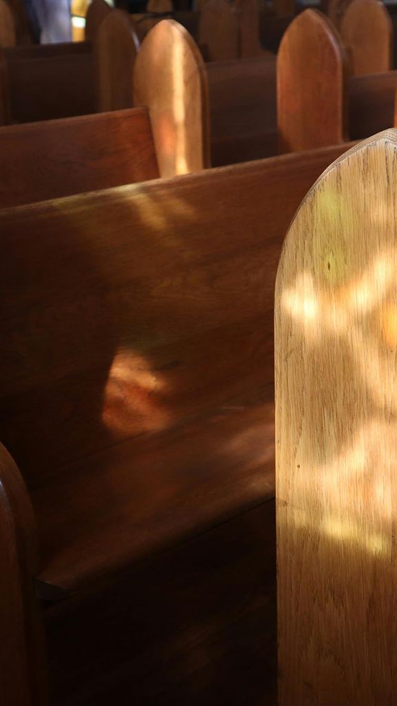 Photo: A picture of open pews with the sun reflecting the light in an empty church.
