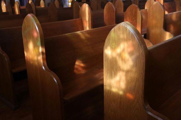Photo: A picture of open pews with the sun reflecting the light in an empty church.