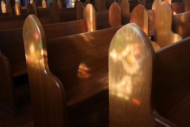 Photo: A picture of open pews with the sun reflecting the light in an empty church.