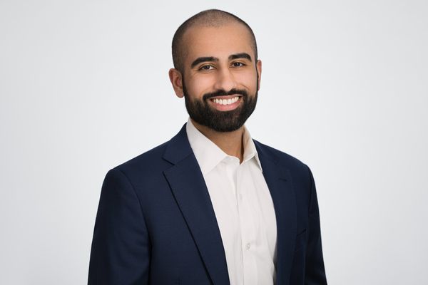 Photo: A headshot of a man in a suti smiling in front of a white background