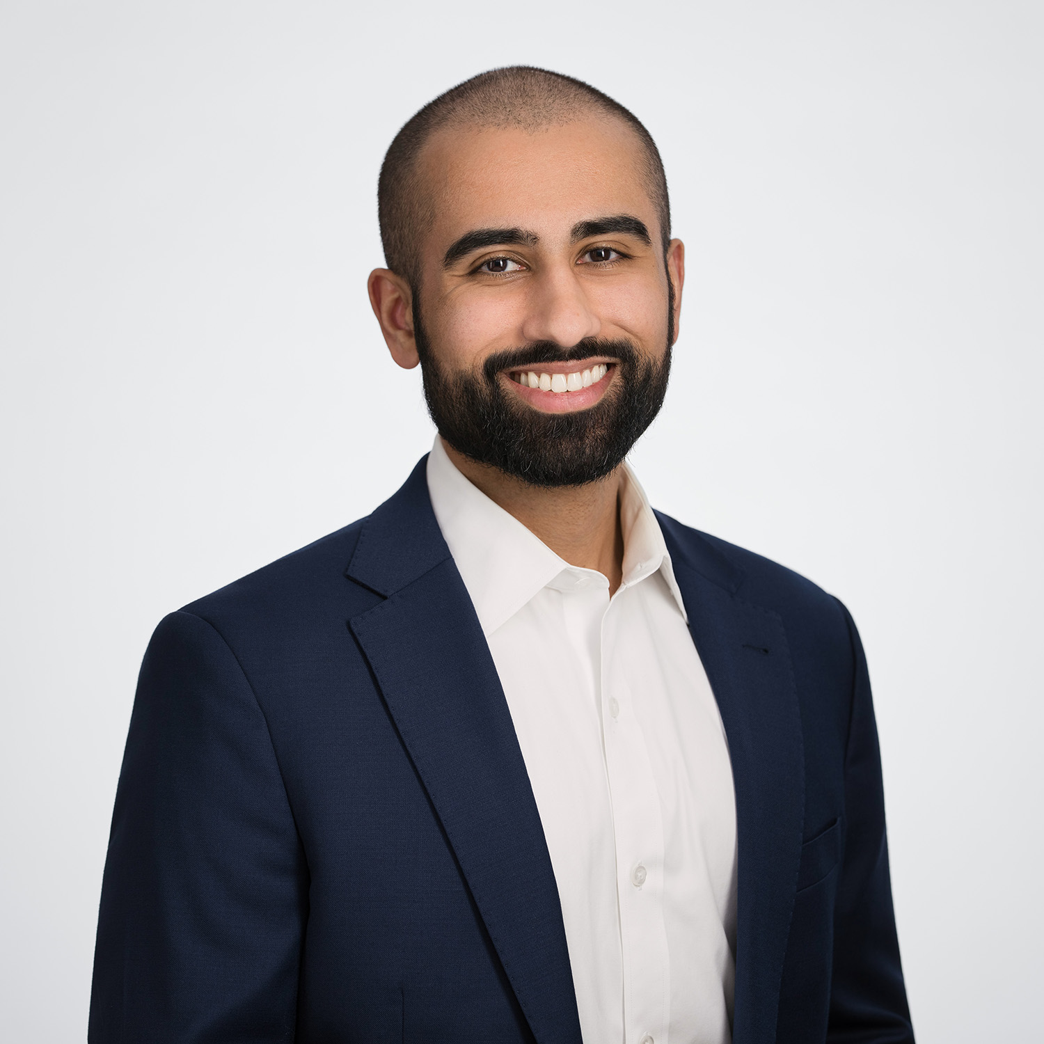 Photo: A headshot of a man in a suti smiling in front of a white background