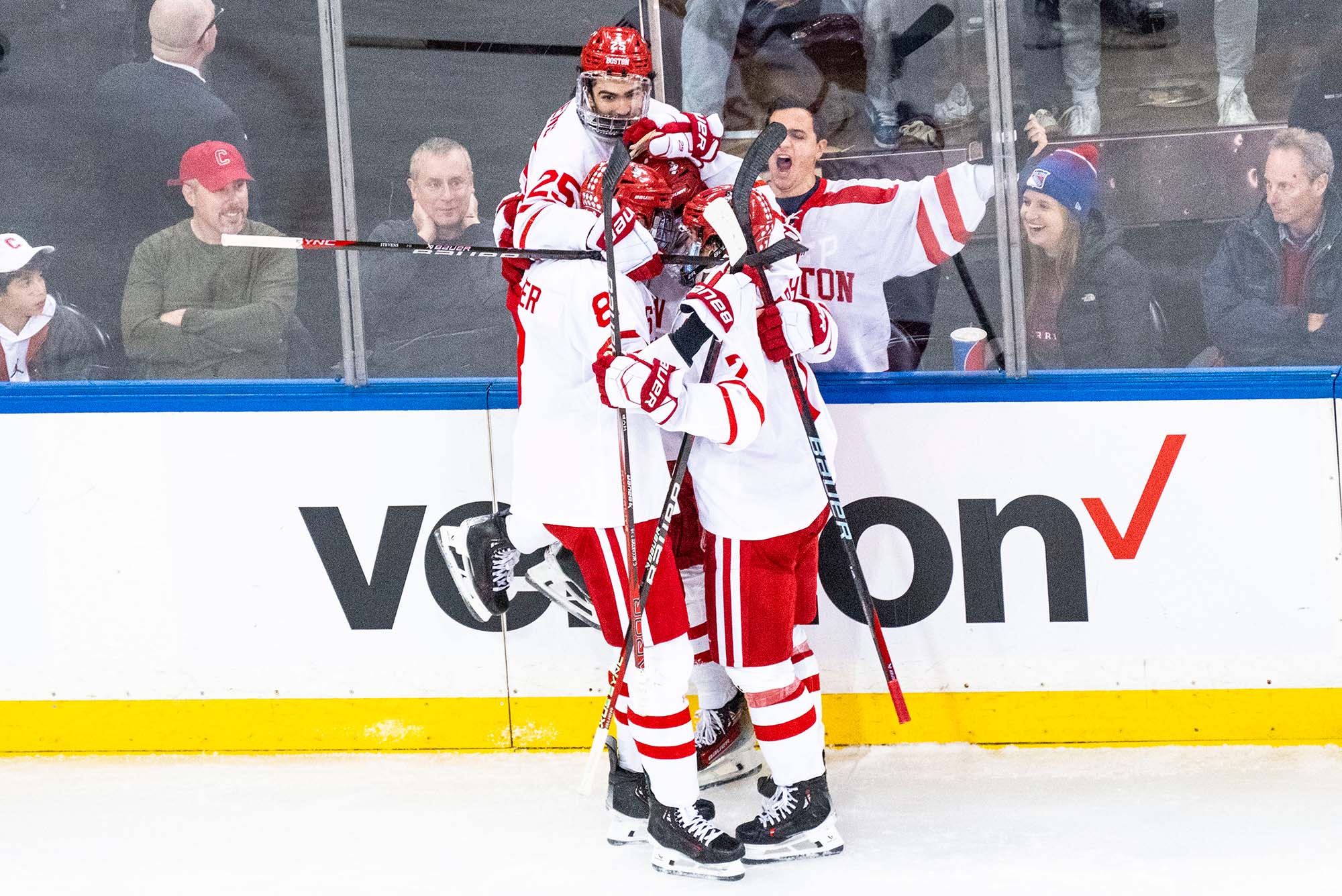 Photo: Members of the BU Men's hockey team embracing in a celebration on the ice