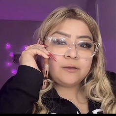 Meme: Person with long blonde hair wearing a black top, sitting in a room with purple lighting and string lights on the wall.
