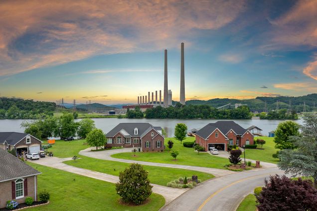 Photo: A shot of a thermal power plant polluting air burning coal fossil fuel for production of electrical energy. A small neighborhood rests in the foreground.