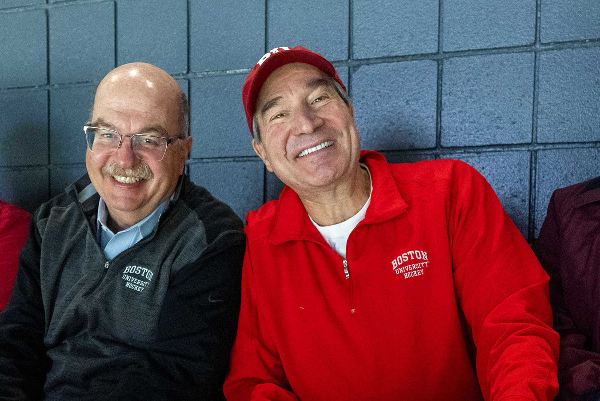 Photo: Two older men in BU hockey gear smiling during a BU hockey game
