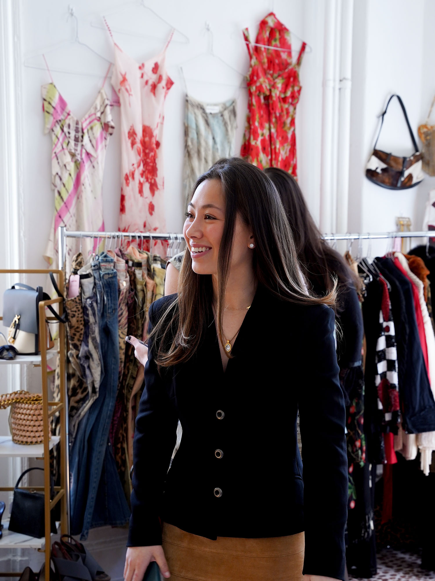Photo: Hana Elster, a Boston University student, in a long-sleeve button down smiling in front of clothing racks