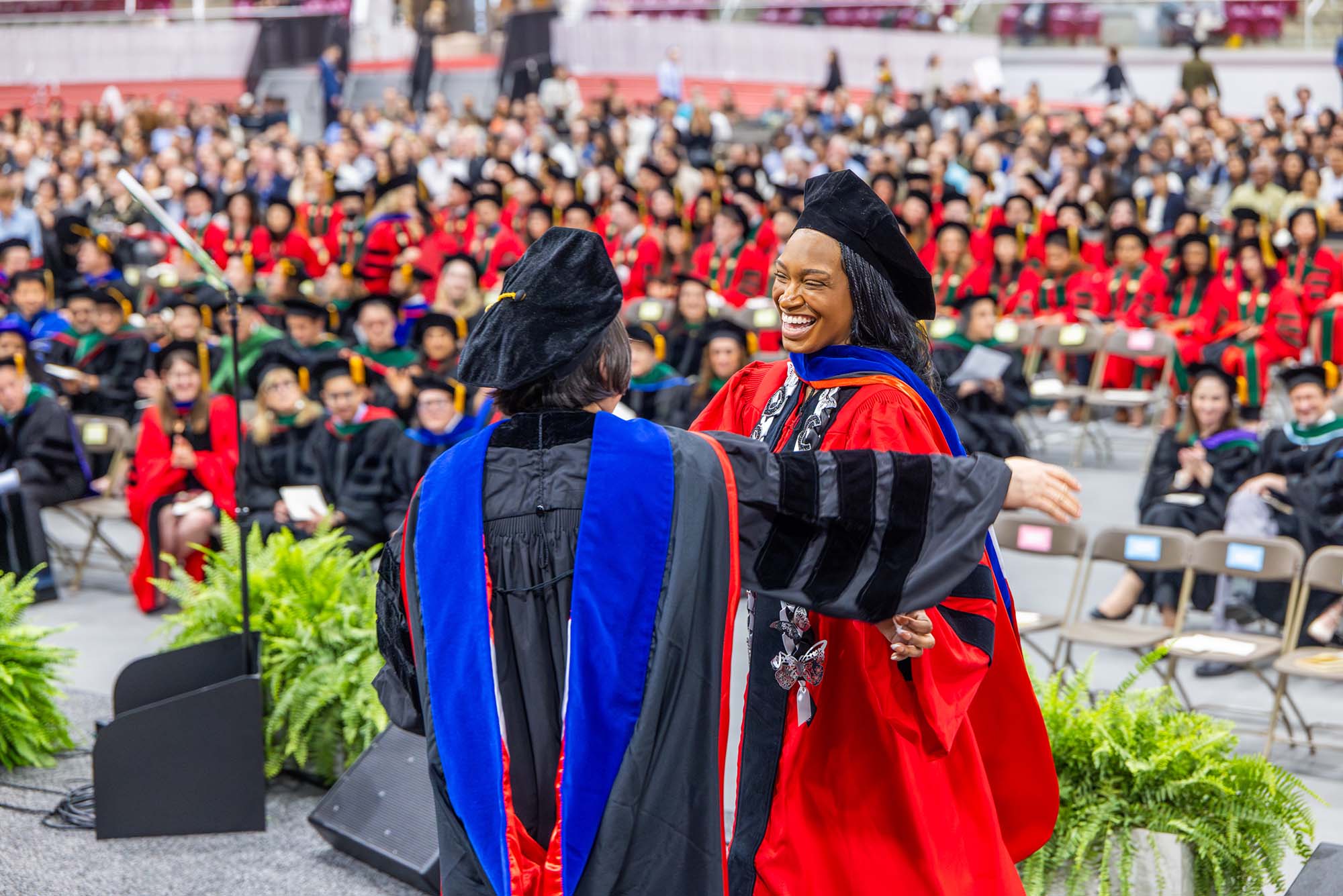 Photo: hinyere Kemet (CAMED’26) receives congratulations from mentor Hui Feng at the school’s MD/PhD convocation held at BU’s Track & Tennis Center