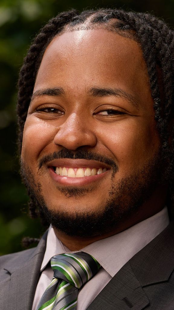 Photo: Stephen Ellis of BU Campus Planning & Operations smiling in a suit in front of greenery