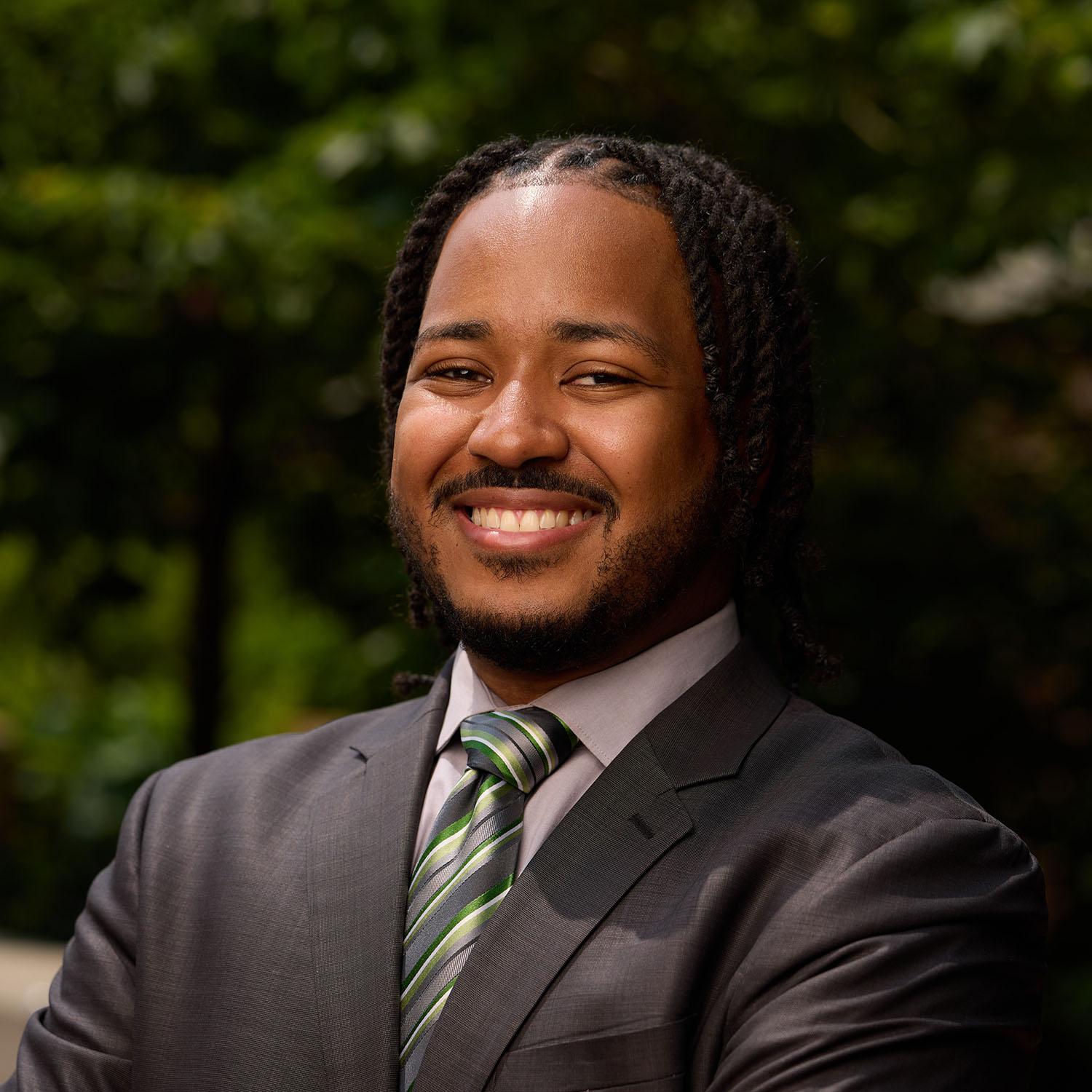 Photo: Stephen Ellis of BU Campus Planning & Operations smiling in a suit in front of greenery