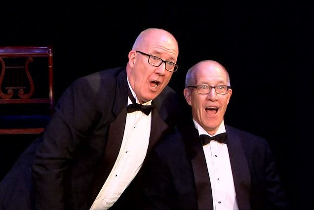 Photo: Twins on a stage performing their personal play in traditional tuxes.