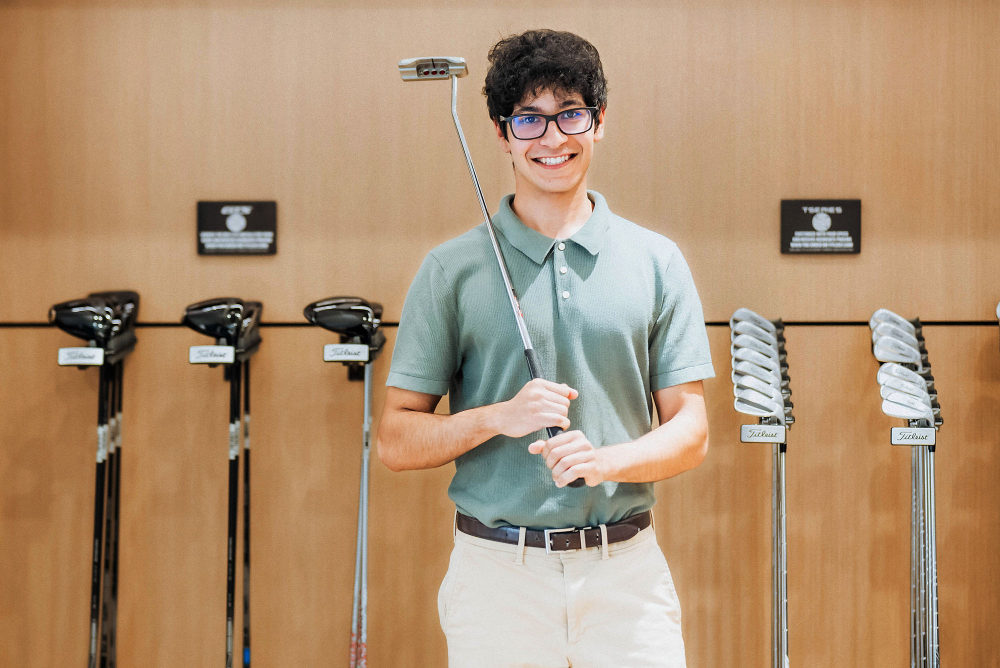 Photo: College student poses holding a golf putter