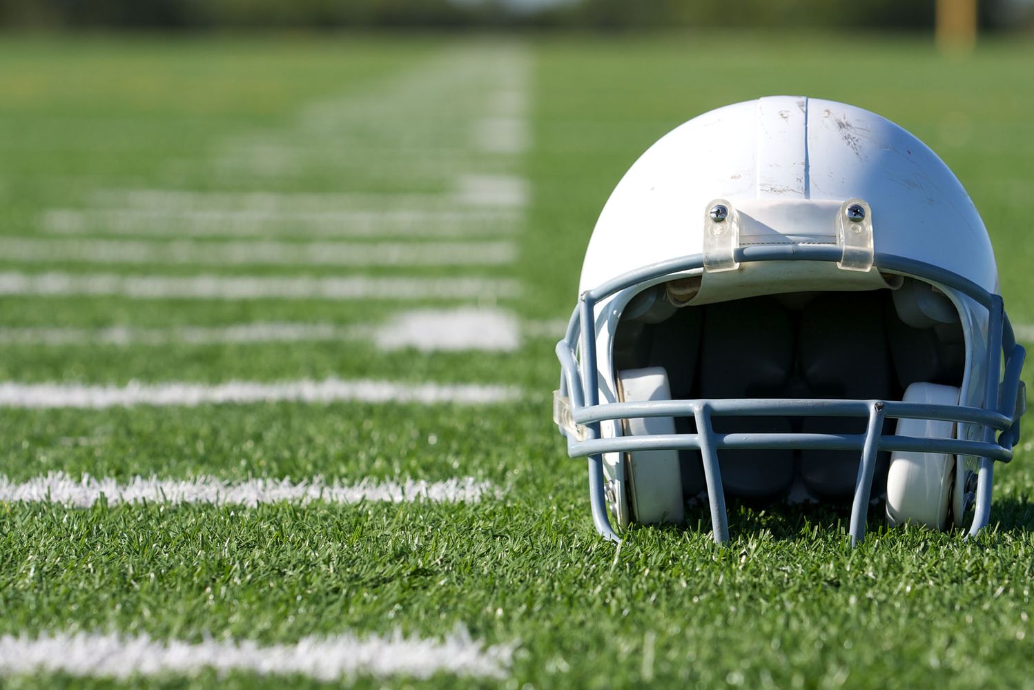 Photo: White american football helmet sitting on a field