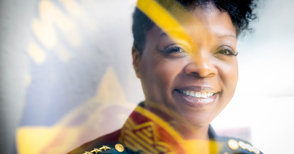 PHOTO: BUPD Deputy Chief Pamela Harris smiles for a radiant portrait with an equally radiant smile. The photo has a stunning lens flare overlayed due to the lighting of the shot.