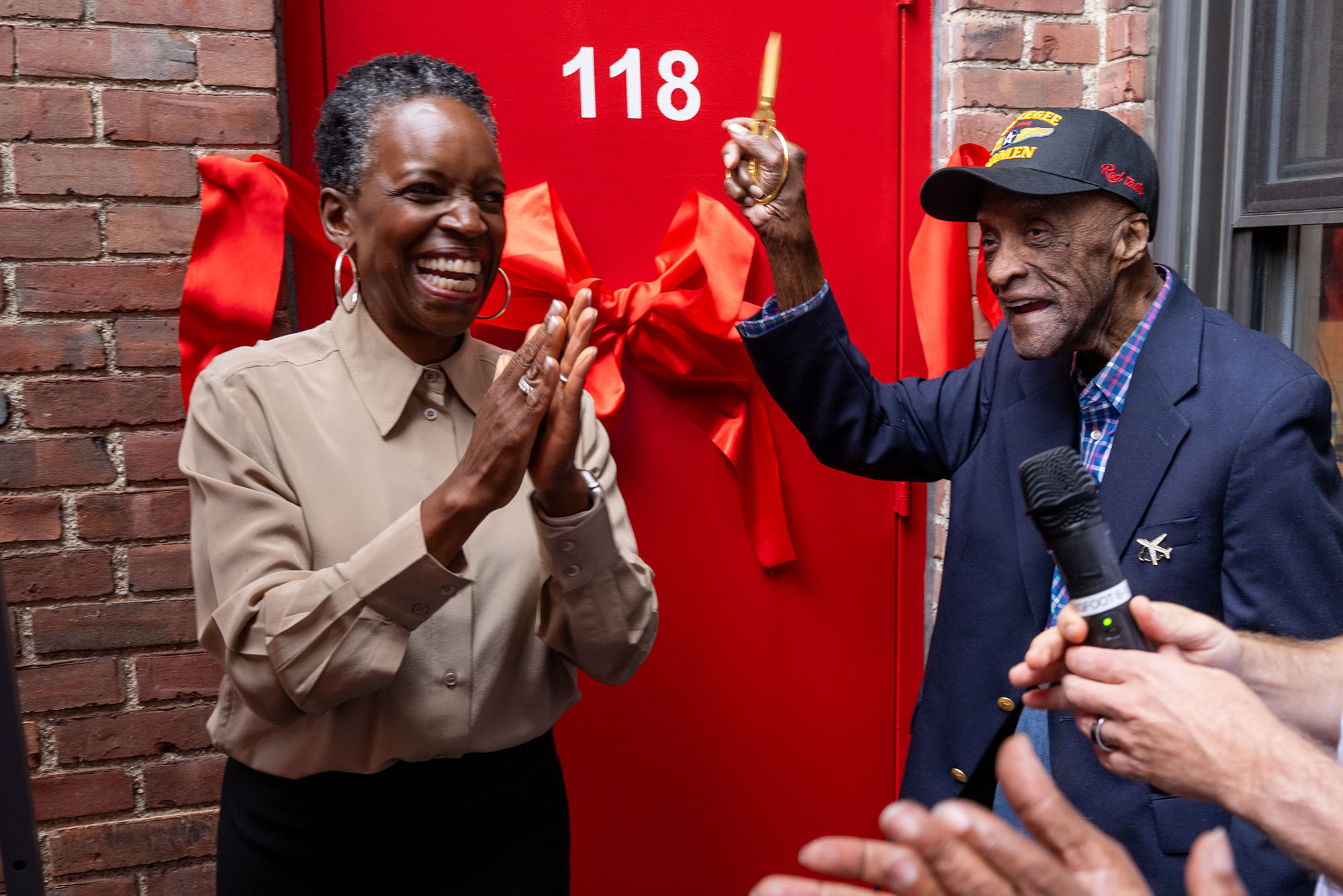 BU President Melissa Gilliam joins alum Brigadier General Enoch "Woody" Woodhouse (LAW'55) at the ribbon cutting for a permanent display of Woodhouse’s military memorabilia on view in the newly named Woodhouse Cadet HQ at the BU Air Force ROTC building at 118 Bay State Road, September 1. At 99, Woodhouse is one of the last surviving members of the Tuskegee Airmen, the famed all-Black World War II fighter squadron. President George W. Bush awarded Woodhouse and the other Tuskegee Airmen the Congressional Gold Medal in 2006. Photo by Cydney Scott