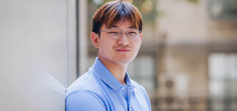 Photo: College freshman Ryan Sim in a blue shirt poses for formal portrait outside on sunny day