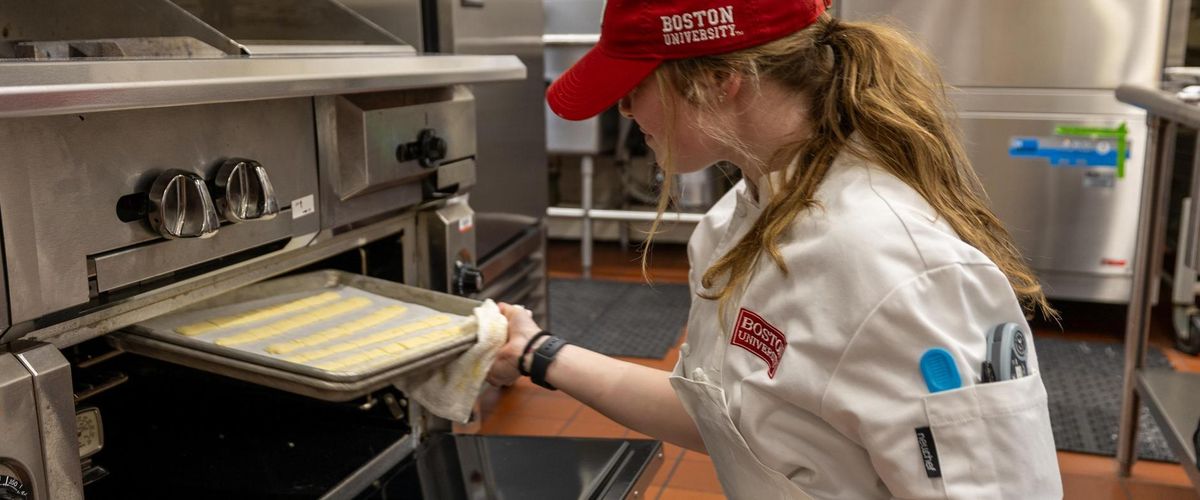 Pastry student working closely with professional oven at Boston University.