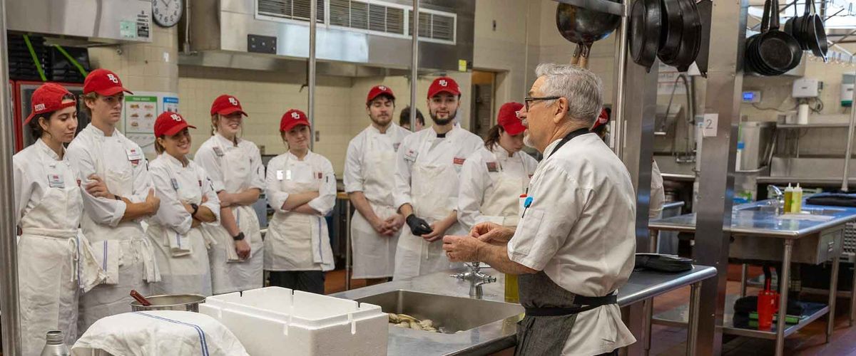 A BU Food Studies faculty member lecturing students in a kitchen