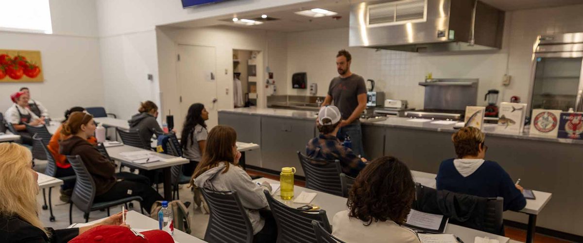 A part-time faculty member lecturing students in BU's test kitchen