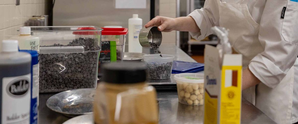 A student measuring baking ingredients on a food scale