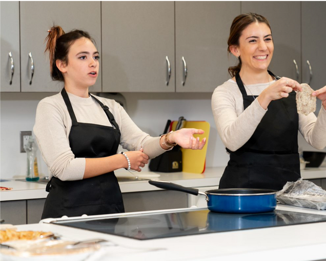 Two people with pan doing a cooking demonstration