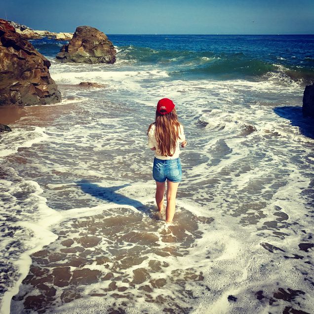 2019 GP Photo Contest Finalist girl standing in the surf wearing a red BU ball cap