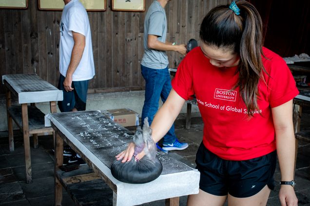 2019 GP Photo Contest Finalist female student wearing BU Pardee T shirt inking a scroll