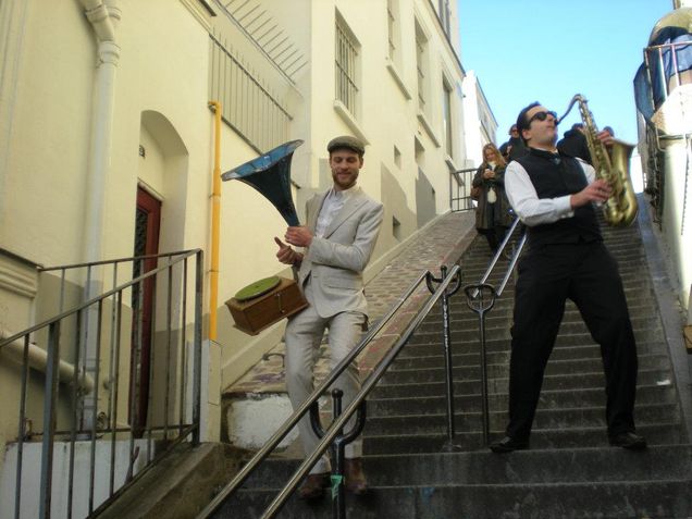 2013 GP Photo Contest Finalist a man playing the saxaphone and a man carrying an old record player walking down the stairs on a street in europee