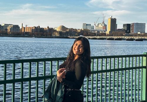 Kuhu standing in front of a river in a city