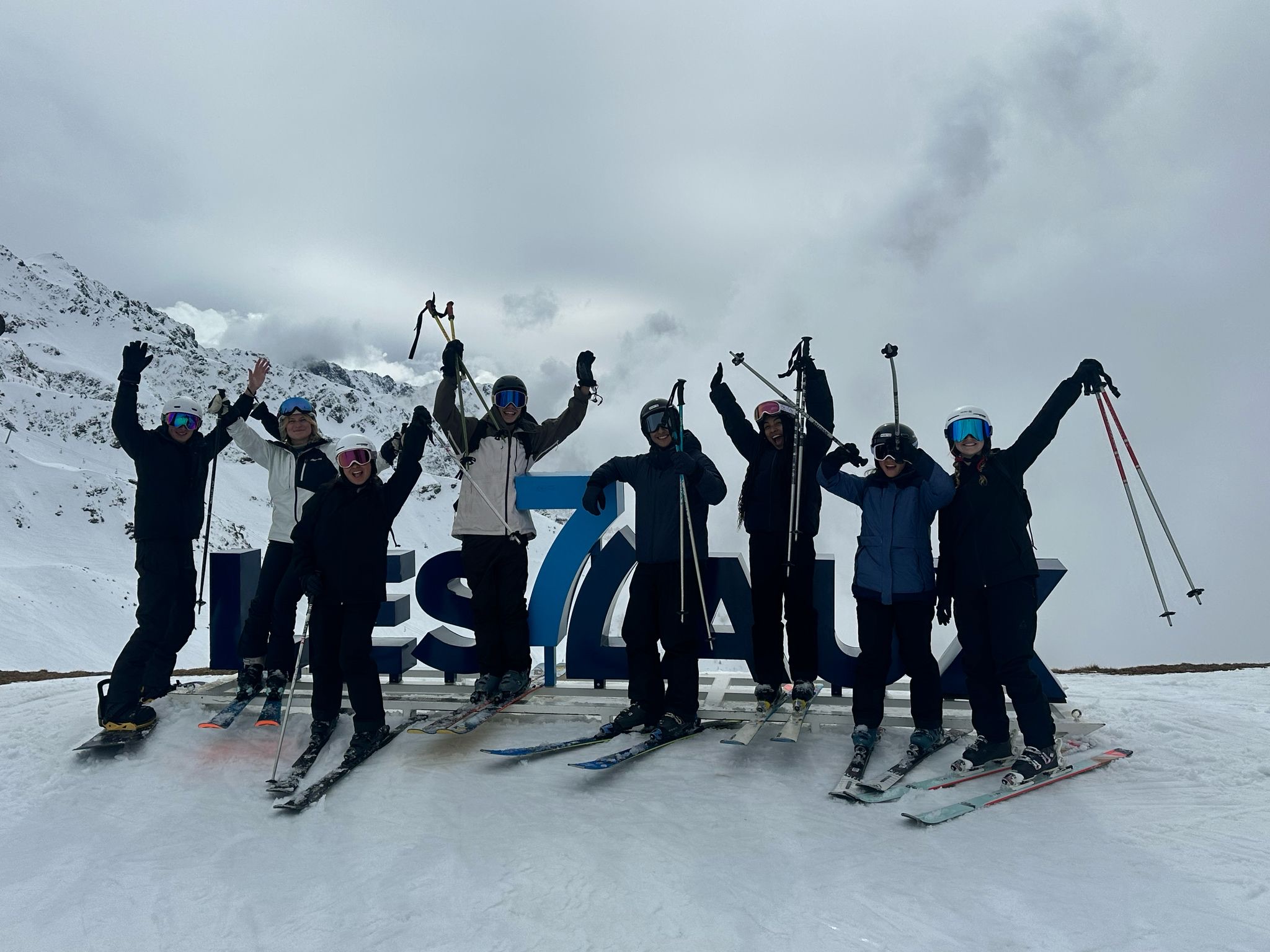 group skiing and posing in front of sign at Les Sept Laux