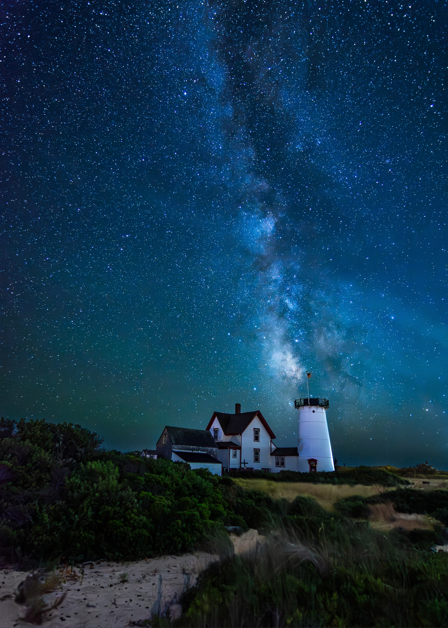 Star filled night sky and lighthouse on a beach in Chatham MA. 2026 GP Photo Contest winner.
