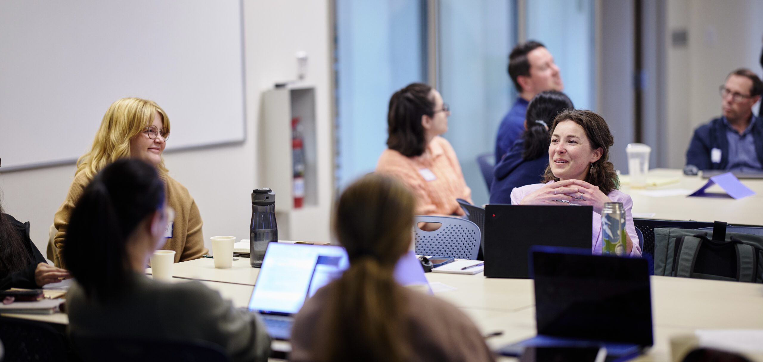 Smiling students converse during a university workshop.