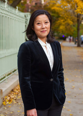 Alice Tseng with shoulder-length brown hair wearing a velvet black suit jacket and white button-up shirt