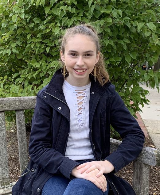 Undergraduate student, Rebecca Kielar, sitting on park bench, smiling. 